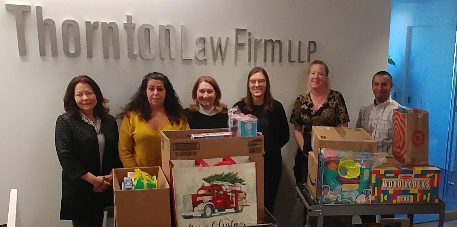 Photo of 6 Thornton Law Firm employees with wrapped Christmas presents for donation